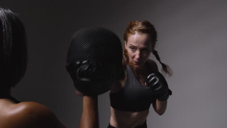 Studio-Shot-Of-Two-Mature-Women-Wearing-Gym-Fitness-Clothing-Exercising-Boxing-And-Sparring-Together-4